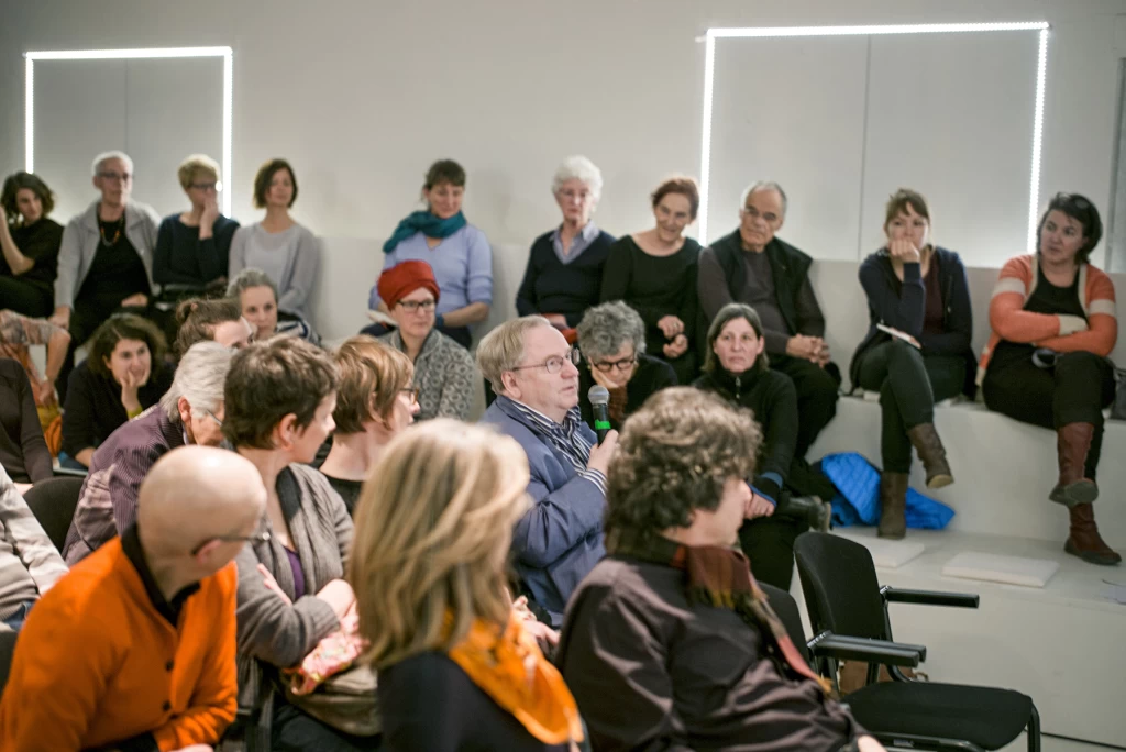 Audience during a discussion, with one person speaking into a microphone.