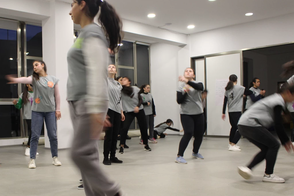 Group of young people taking part in a movement exercise in a bright dance studio.