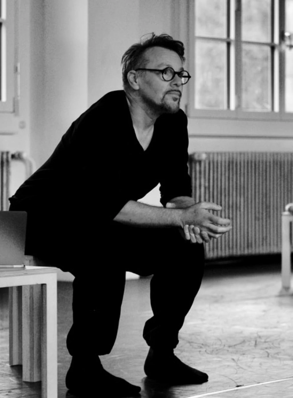 Black-and-white image of Jochen Heckmann sitting on a chair and leaning forward.